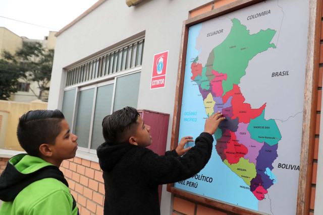 Venezuelan migrant child Ender Rojas shows his friend Isaac Fuentes the route he took from Trujillo, Venezuela, to Lima at the inauguration of a temporary shelter in Lima