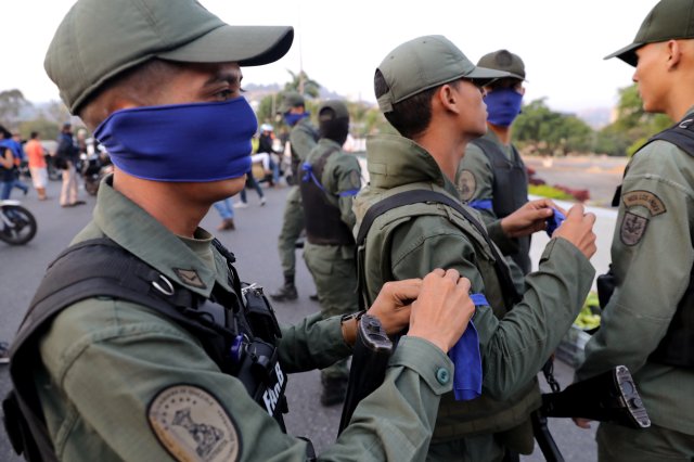 Military members place a blue arm band near the Generalisimo Francisco de Miranda Airbase in Caracas