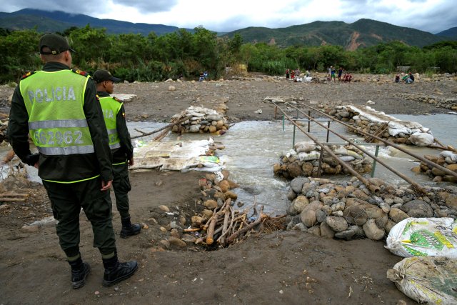 Colombian police officers look on the remains of an improvised road over the Tachira River on the Colombian-Venezuelan border, from the outskirts of Cucuta